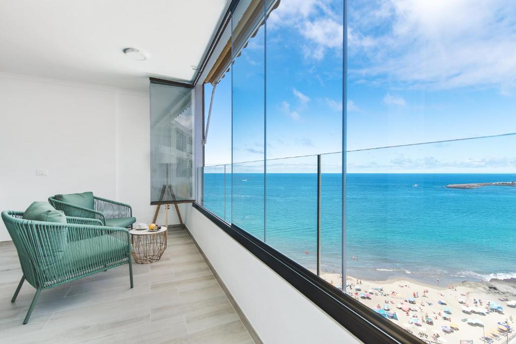 Un balcón con una silla y vistas al océano. en Home2Book Blue Sea View Patalavaca Beach Apartment, en Patalavaca