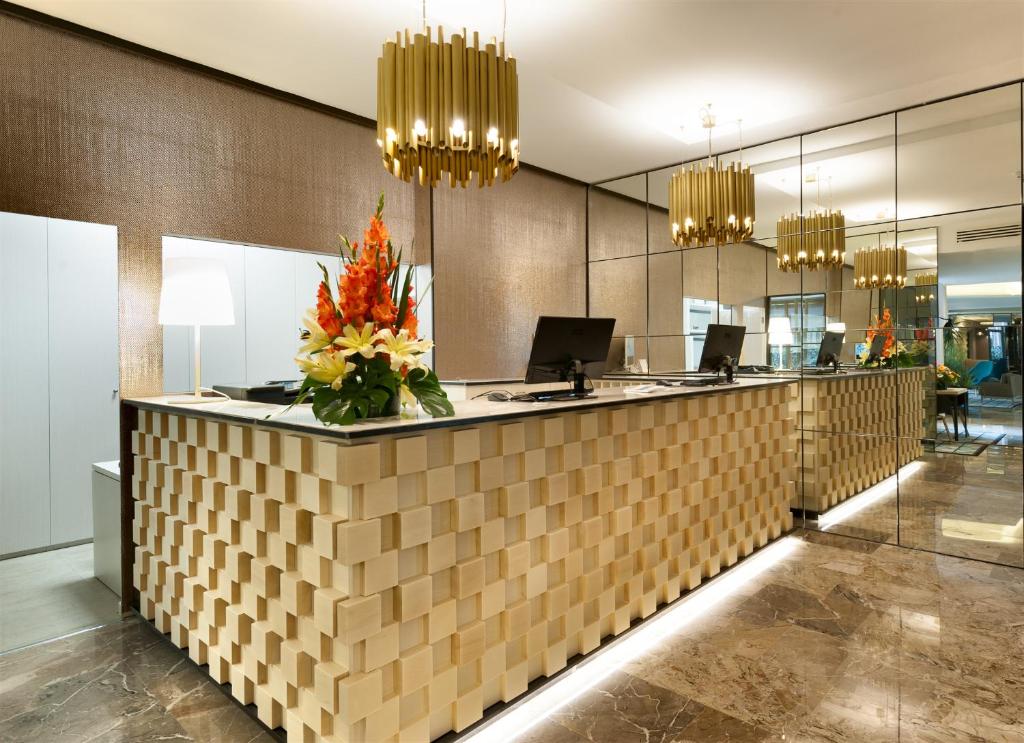 a lobby with a reception counter with flowers on it at Hotel Lombardia in Milan