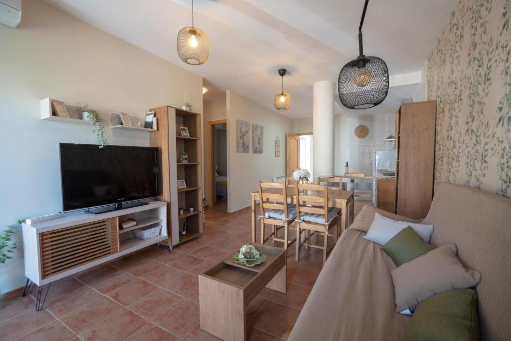 a living room with a couch and a television and a table at VFT Apartamento "La Dehesa de Cazorla" in Burunchel