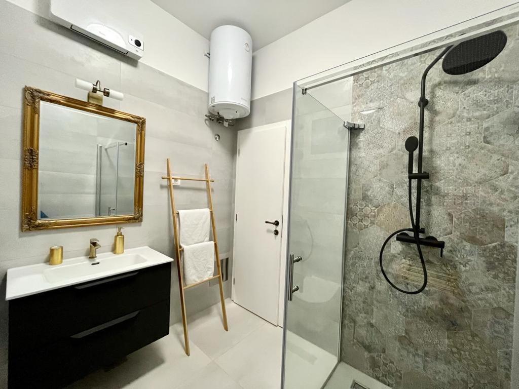 La salle de bains est pourvue d'un lavabo et d'une douche avec un miroir. dans l'établissement Lux Apartmans, à Pula