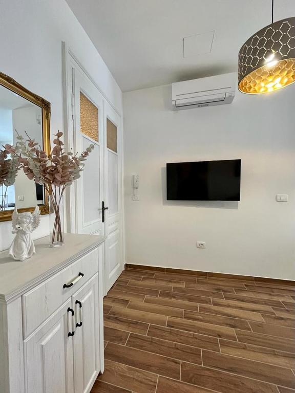 kuchnia z białymi szafkami i telewizorem na ścianie w obiekcie Lux Apartmans w Puli