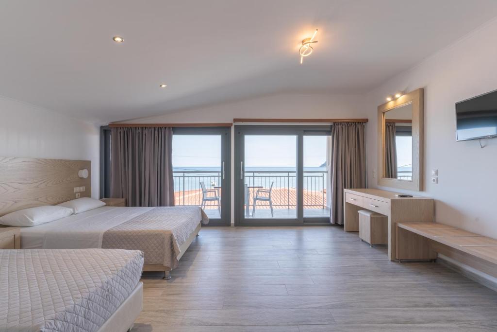 a hotel room with two beds and a balcony at Mandala Seafront Suites in Laganas