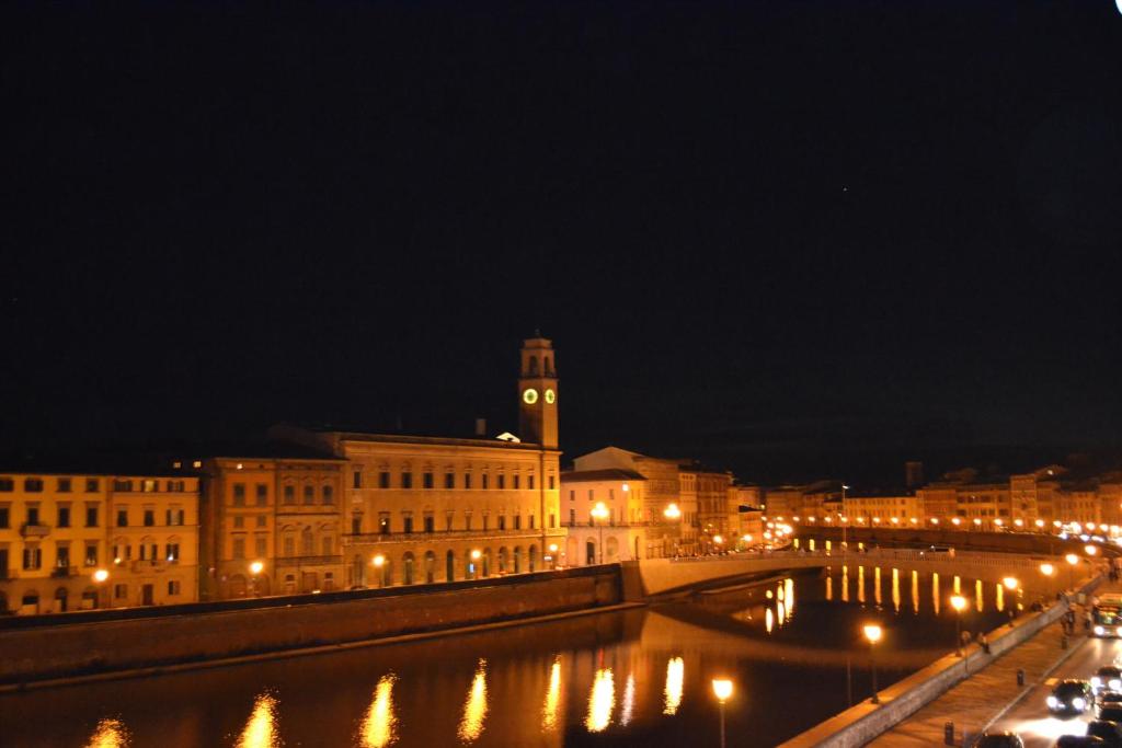 una ciudad iluminada por la noche con una torre de reloj en You & Me, en Pisa