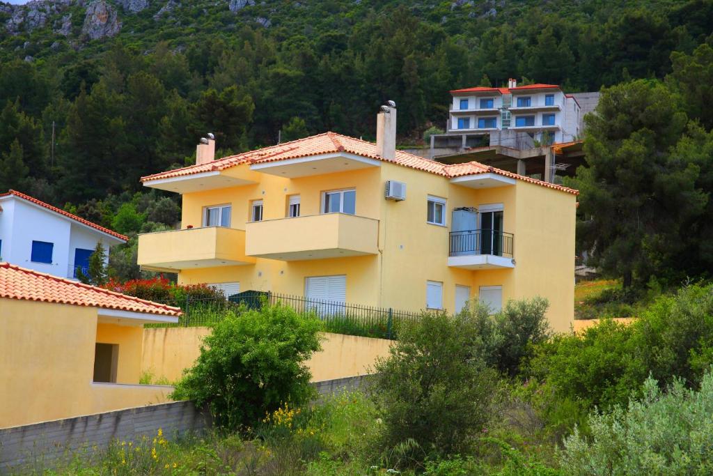 una casa amarilla en una colina con casas en el fondo en Apartment in Theologos, en Theológos