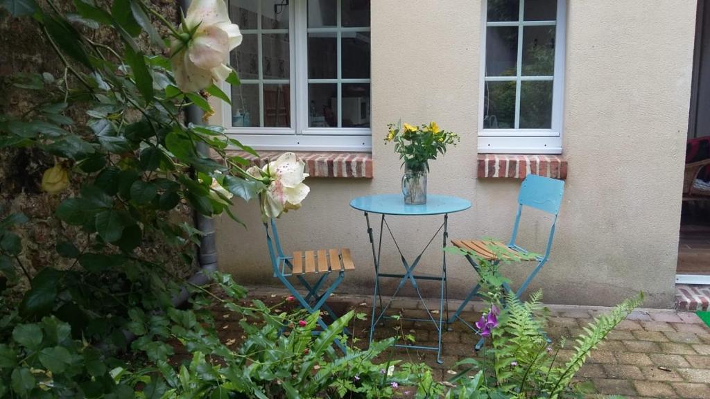 d'une table et de deux chaises avec un vase de fleurs. dans l'établissement La cabane du Petit Matelot, à Honfleur
