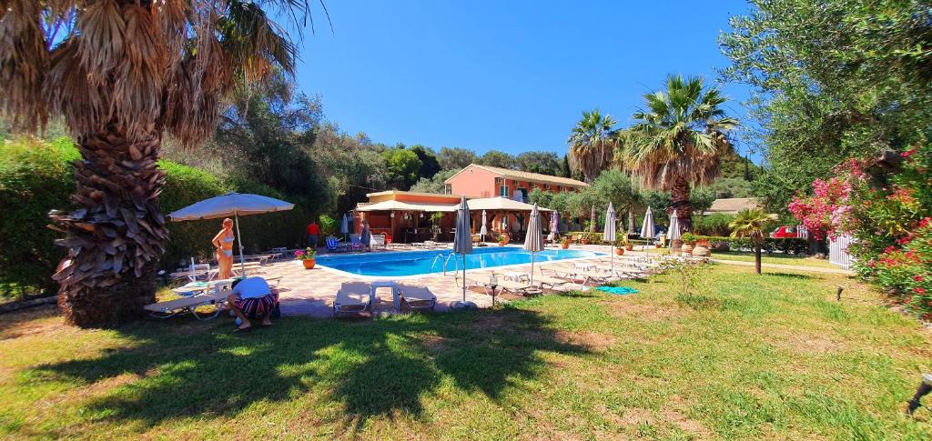 un homme debout près d'une piscine dans une cour dans l'établissement Phivos Hotel, à Paleokastritsa