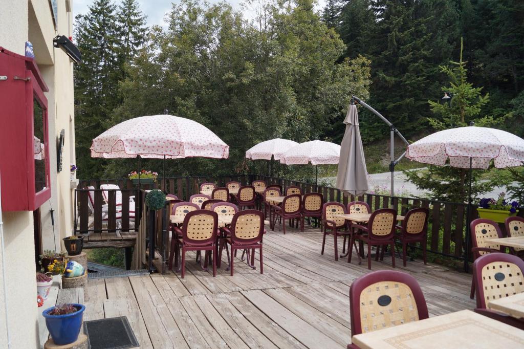 a bunch of tables and chairs with umbrellas on a deck at Hotel - Restaurant Le Blanchon in Selonnet