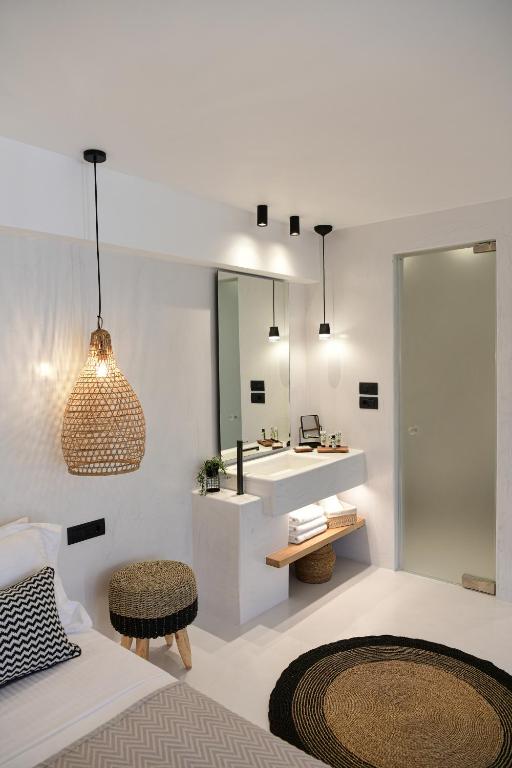 a bedroom with a bathroom with a sink and a mirror at Ios Art Suites in Ios Chora