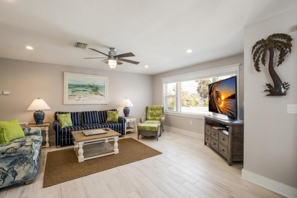 a living room with a couch and a tv at Royal Palm: Pool, 2 Blocks to Beach, Close to Dining & Shopping by Anna Maria Life Vacation Rentals in Holmes Beach