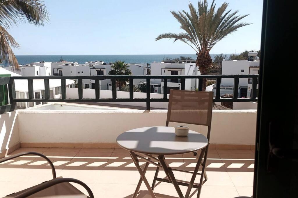 uma mesa e cadeiras numa varanda com vista para o oceano em TUSCAN Apartment mit Meerblick und Sonnenterrasse em Costa Teguise