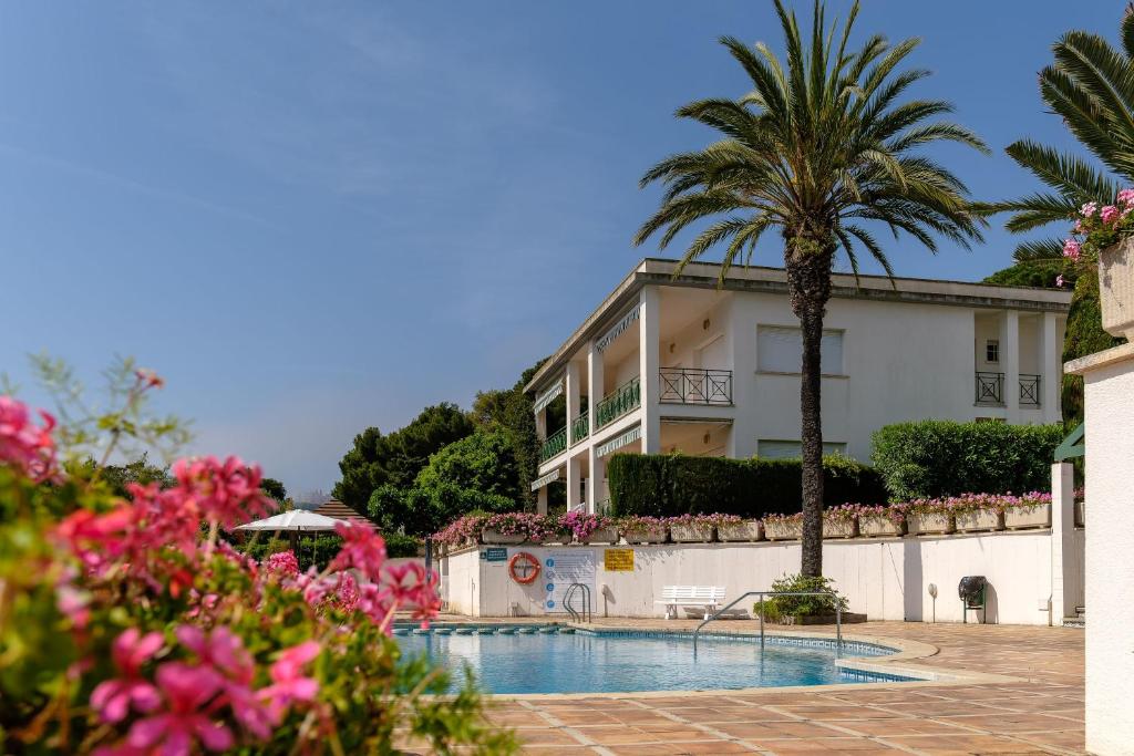 um edifício com uma palmeira ao lado de uma piscina em Bravissimo Estel B4 S'Agaró em S'agaró