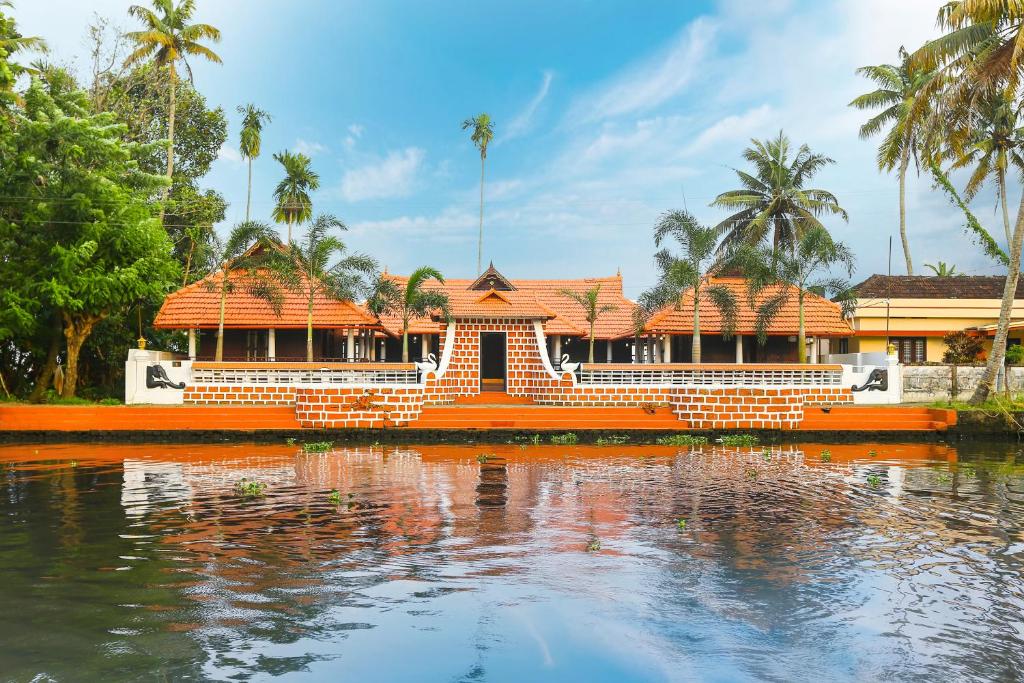 un bâtiment orange au milieu d'une masse d'eau dans l'établissement Palmy Lake Resort, à Alappuzha