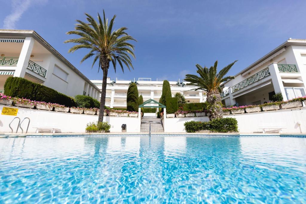 - une piscine en face d'un bâtiment avec des palmiers dans l'établissement Bravissimo Estel A6 S'Agaró, à S'Agaro