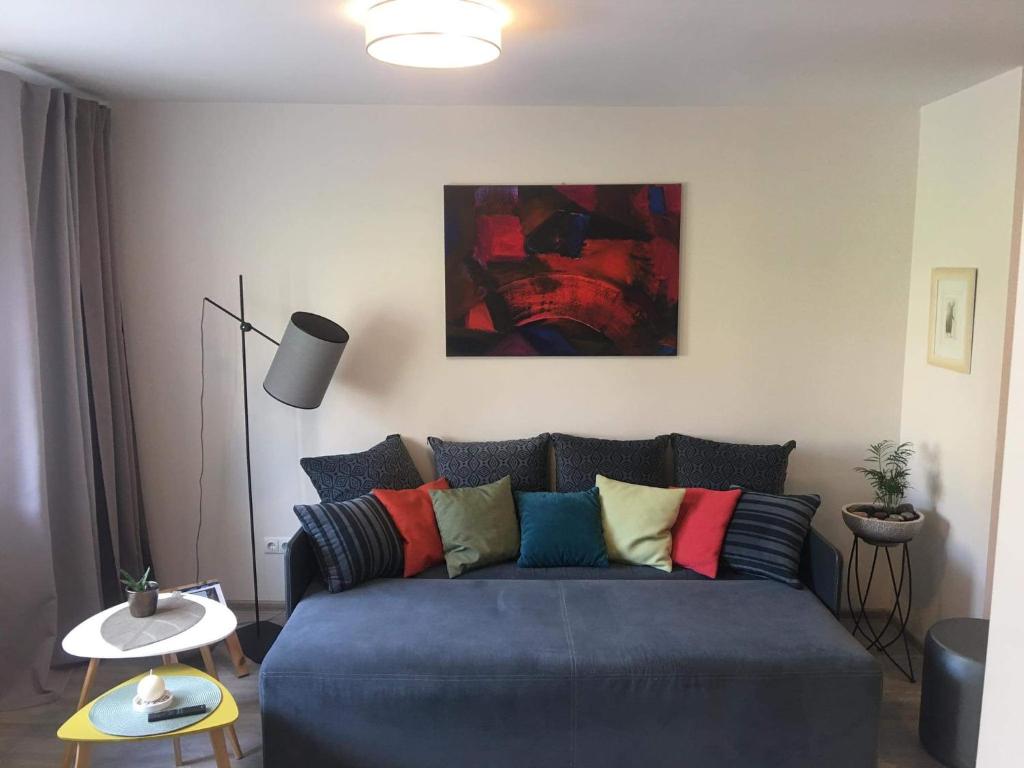 a living room with a blue couch with colorful pillows at Smiltės apartamentai in Birštonas