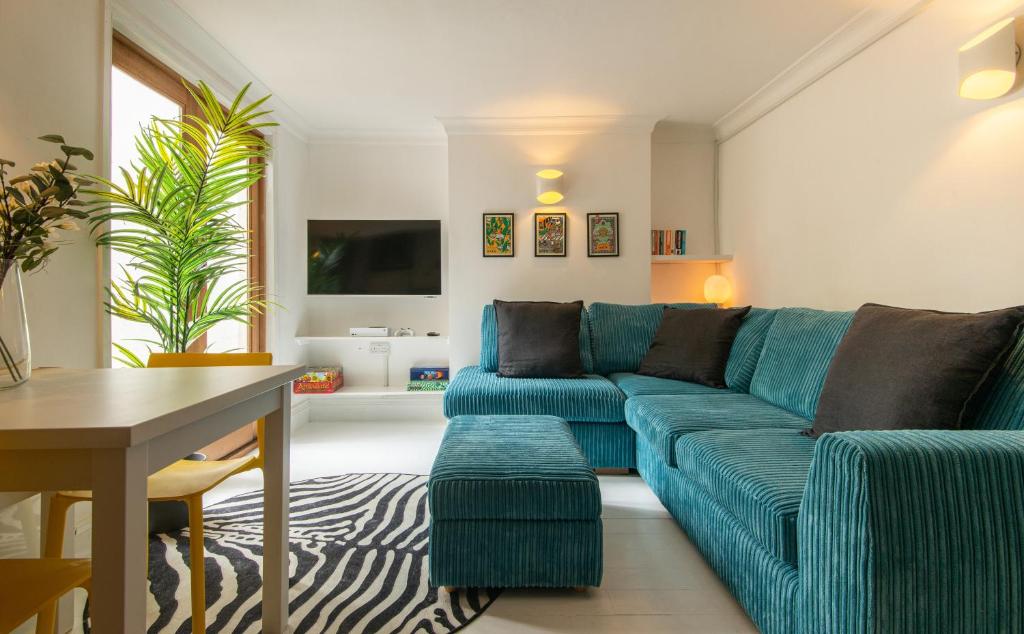 uma sala de estar com um sofá azul e uma mesa em -NEWLY REFURBISHED- Stylish Apartment 5 minutes from Station w Garden em Brighton & Hove