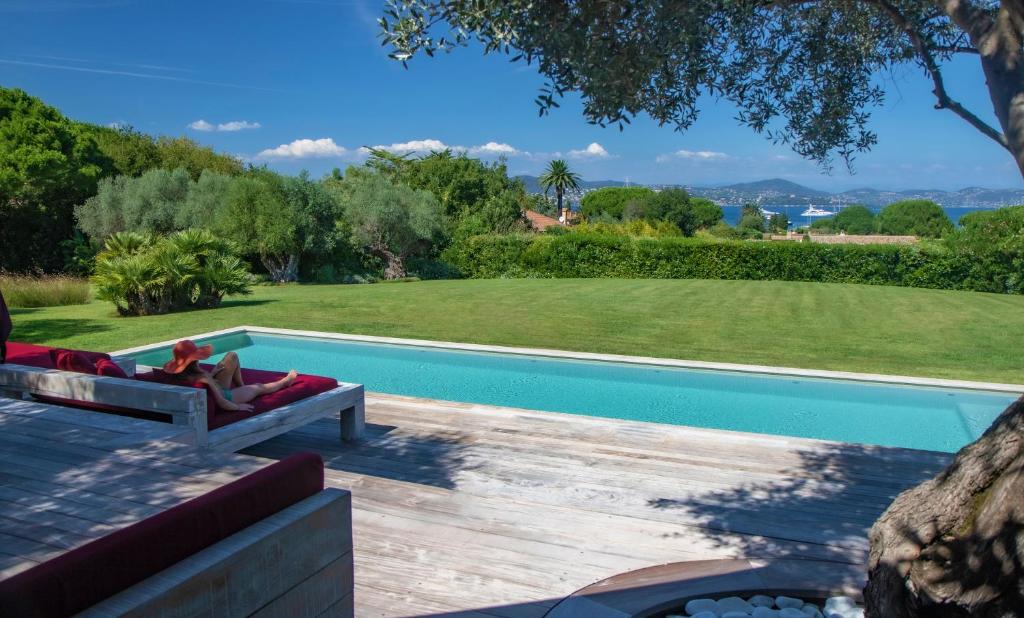 eine Frau auf einem Stuhl neben einem Pool in der Unterkunft Vyylla Private Resort in Saint-Tropez