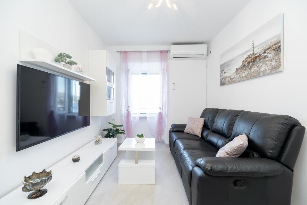 a living room with a black leather couch and a tv at Apartman Stela in Korčula