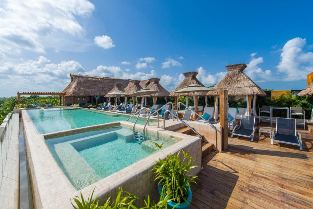 圖盧姆的住宿－Naay Tulum Curamoria Collection，度假村的游泳池,配有椅子和遮阳伞