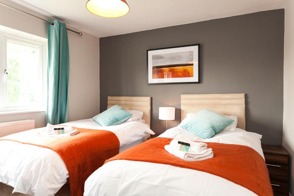 una camera con 2 letti arancioni e bianchi di Comfortable Contractor House Gatwick: sleeps 6+ a Ifield