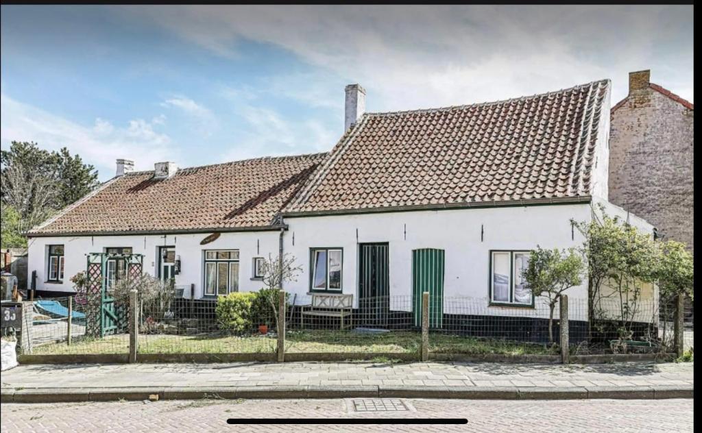 una casa bianca con una recinzione di fronte di t Hoeveke a Ostenda