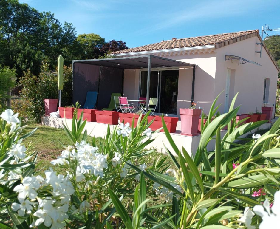una piccola casa bianca con un cortile fiorito di Le MARINE a Saint-Martin-dʼArdèche