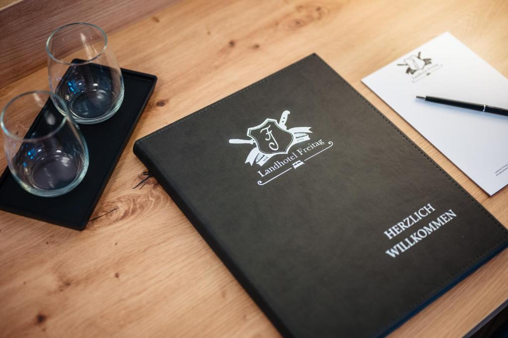 un tavolo con due bicchieri di vino e un libro di Landhotel Freitag a Sankt Paul im Lavanttal