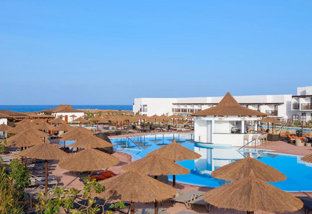 a resort with a pool with straw umbrellas and chairs at Melia Llana Beach Resort & Spa - Adults Only - All Inclusive in Santa Maria