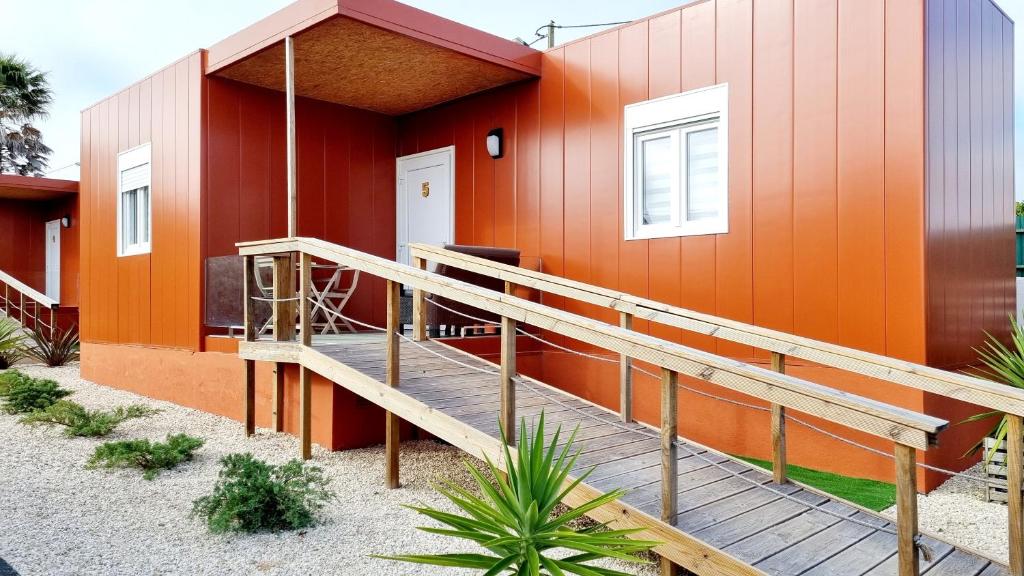 une maison orange avec une rampe en bois devant elle dans l'établissement Family Surf Home - Bungalow 5 - Aulas de Surf, piscina e bicicleta, à Ribamar