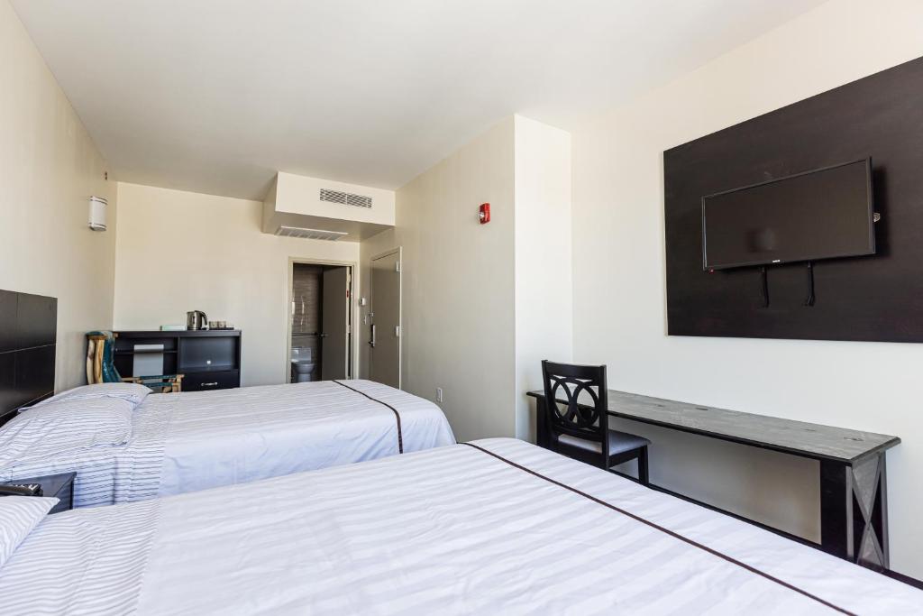 a room with two beds and a desk and a tv at Astoria Inn LaGuardia Hotel in Steinway