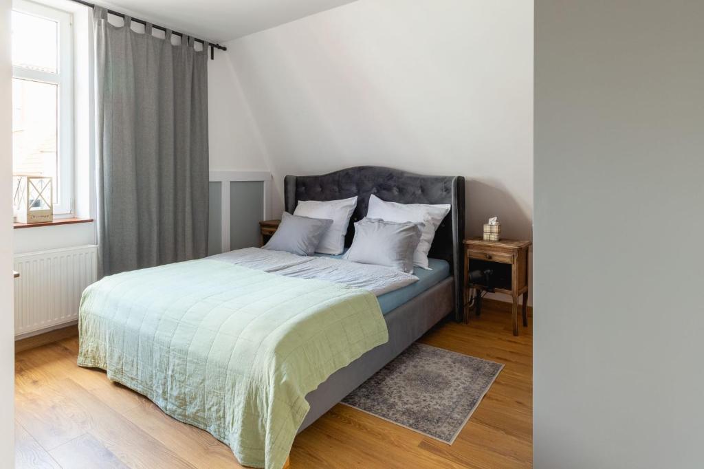1 dormitorio con 1 cama con sábanas blancas y ventana en Kamienica Stare Miasto- Św . Ducha. en Elblag