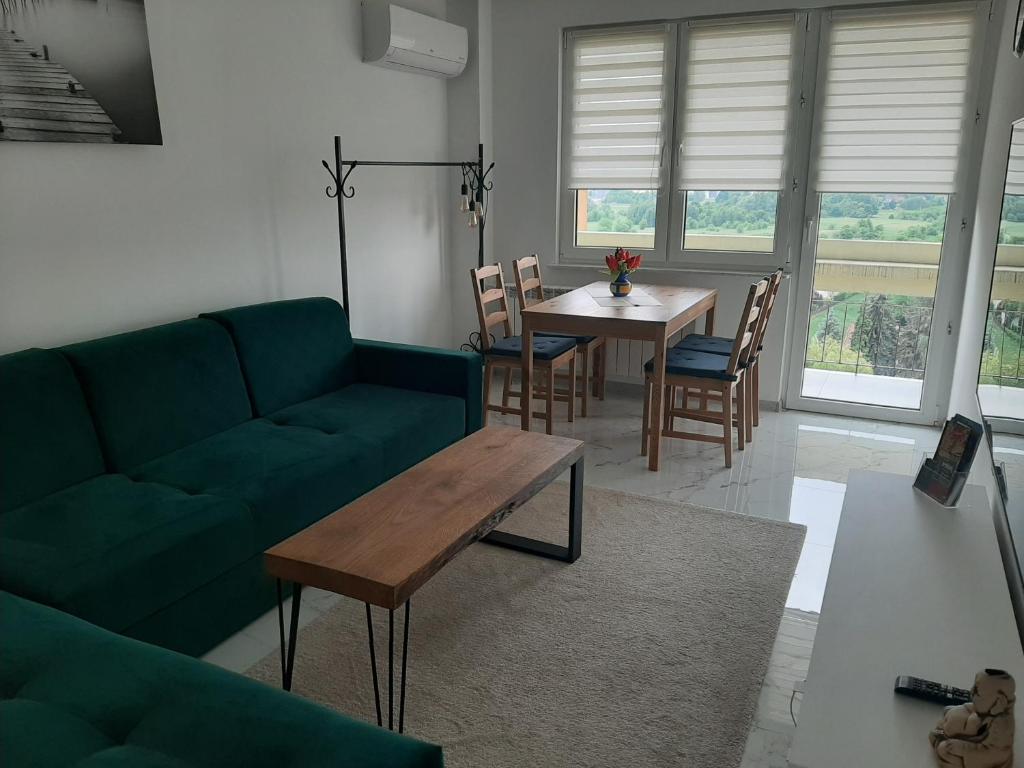 ein Wohnzimmer mit einem grünen Sofa und einem Tisch in der Unterkunft Apartament na 9. piętrze in Oświęcim