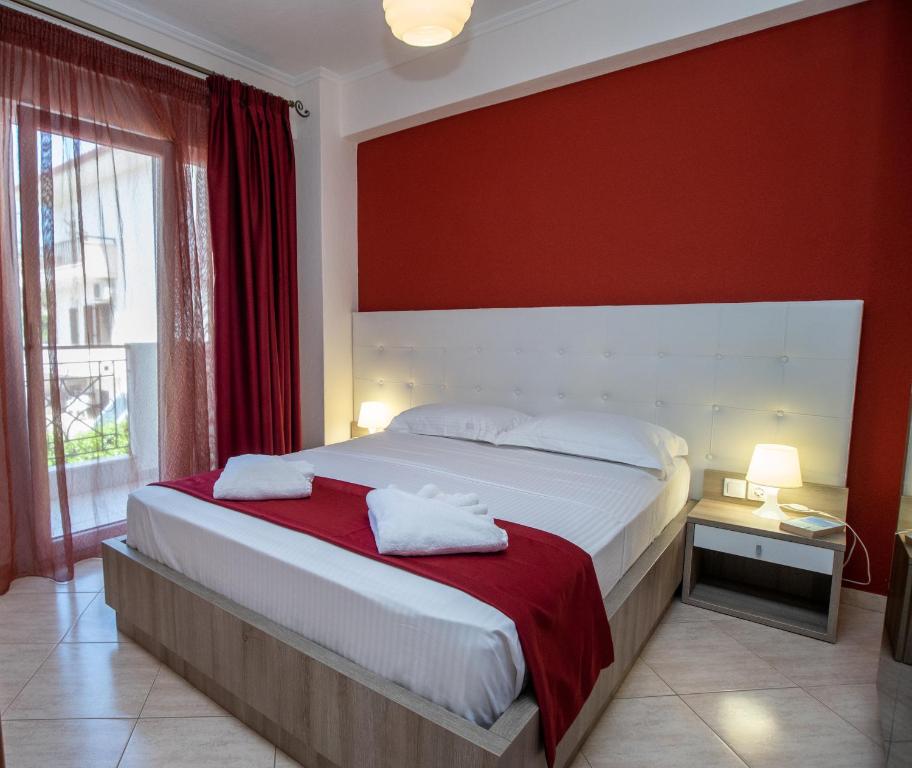 una camera con un grande letto con una parete rossa di Lagaria Apartments ad Áfitos