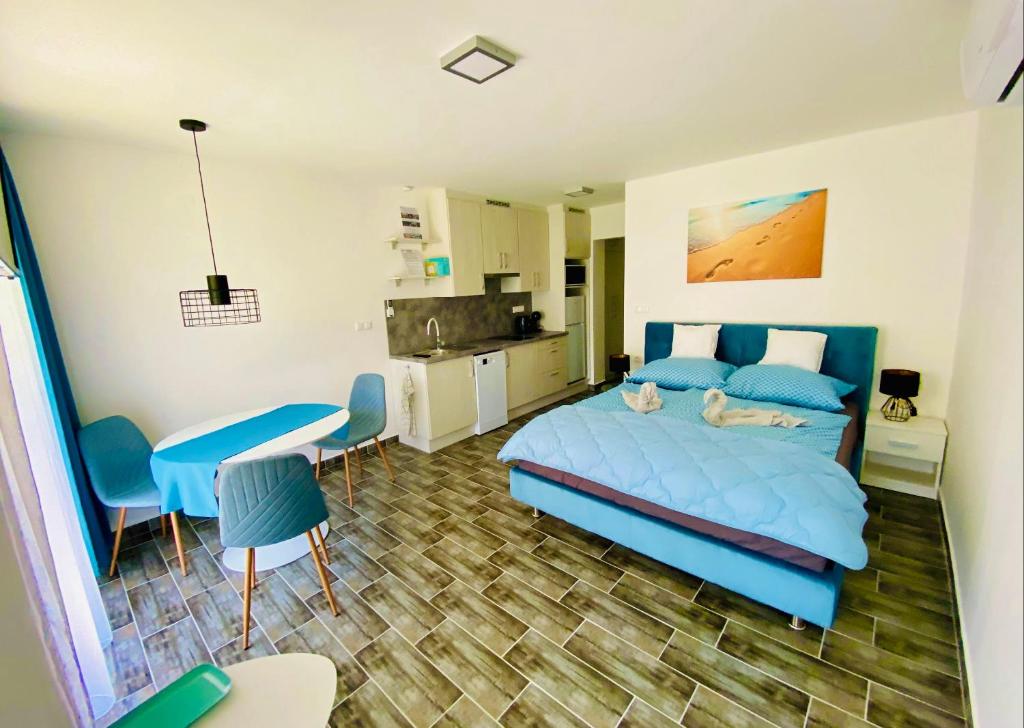 a bedroom with a blue bed and a kitchen at Lilac Apartman in Balatonlelle