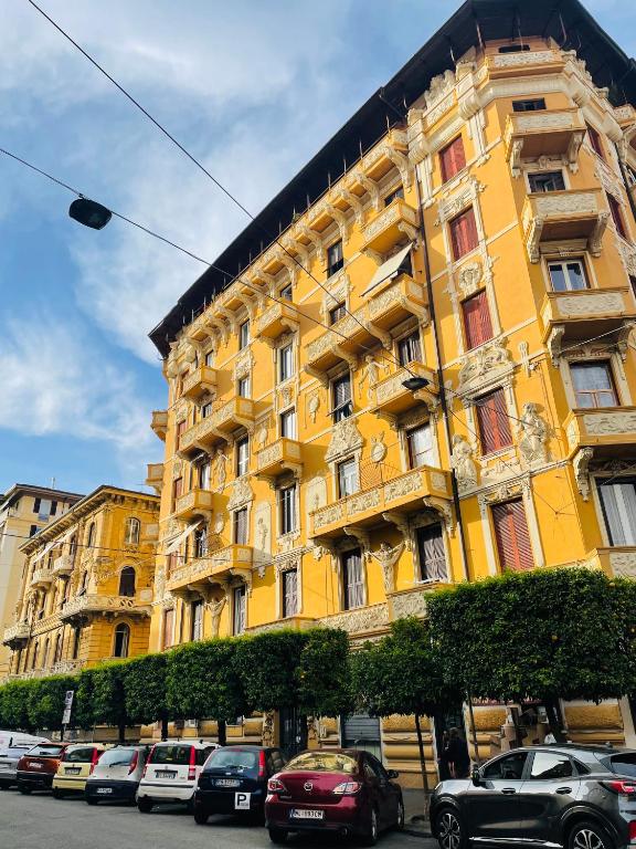 a yellow building with cars parked in front of it at Appartamento retrò-chic in La Spezia in La Spezia