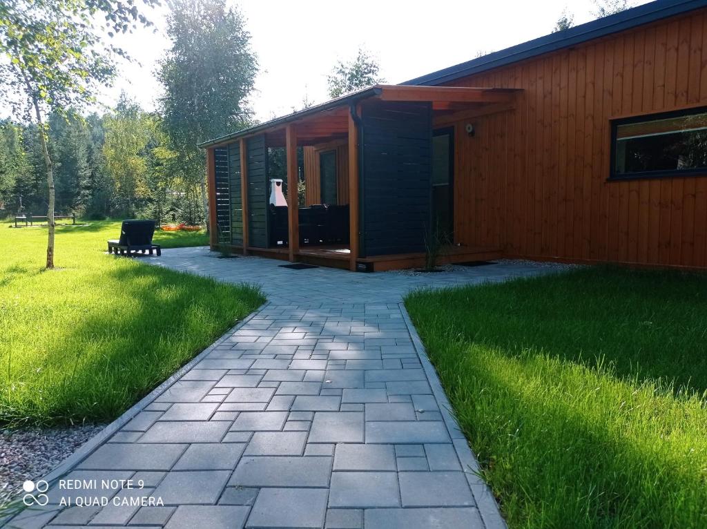 een klein huis met een patio en gras bij ApartDomek CICHE in Zbiczno