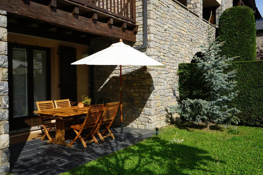 una mesa y sillas con una sombrilla en el patio en Apartamento con jardín en la Cerdanya, en Err