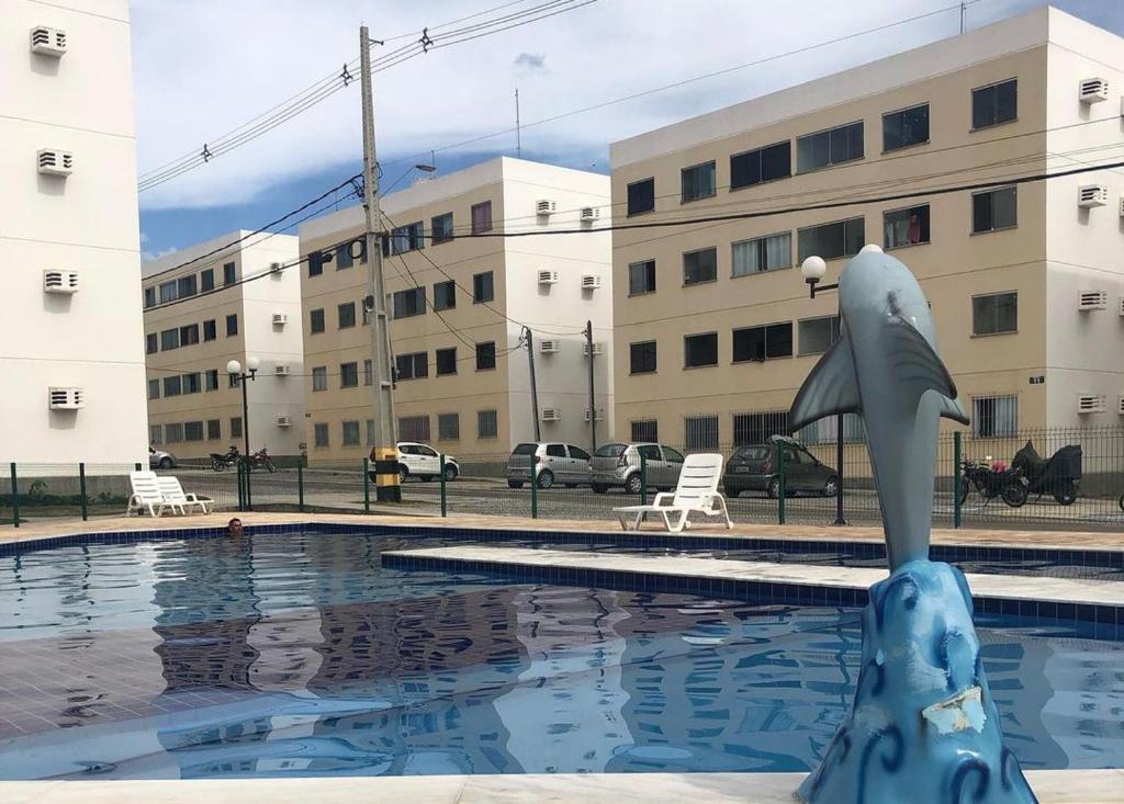 Apartamento Mobiliado para seu conforto في كاروارو: تمثال دلفين في مسبح امام مبنى