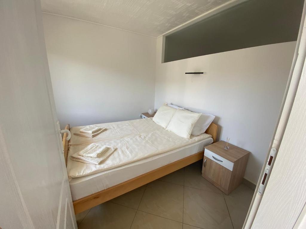 um pequeno quarto com uma cama e uma mesa de cabeceira em Apartmani Bambi Sokobanja em Sokobanja