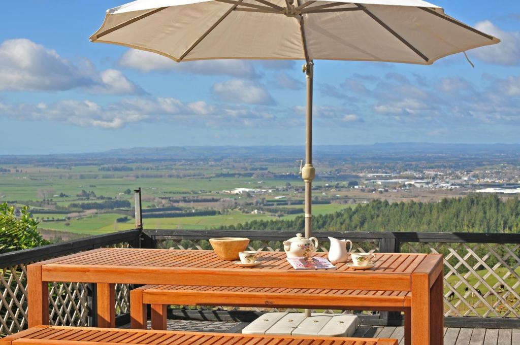 - une table en bois avec un parasol sur le balcon dans l'établissement Warwick Hills Rural Bed & Breakfast, à Papamoa