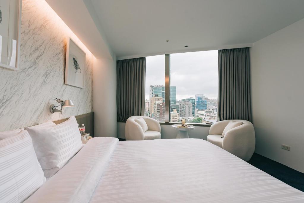 a hotel room with a bed and two chairs and a window at 美寓藝術文旅 Meistay Art Gallery Hotel in Taipei