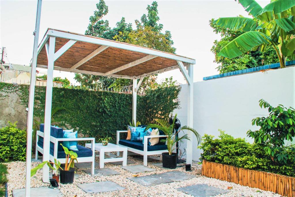 a pergola with chairs and a table in a garden at Eventuality B&B New Kingston in Kingston