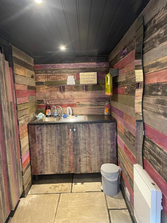 a bathroom with a sink and wooden walls at Rhodes To Serenity - Waterfall Shepherds Hut in Cauldon