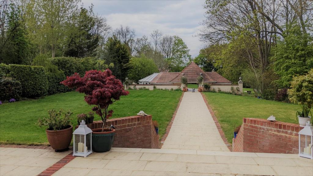 Greater London Villa في Chelsfield: حديقة بها منزل وطريق من الطوب