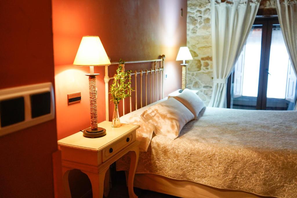 a bedroom with a bed and a table with a lamp at Hotel Rural El Zaguán in Lerma