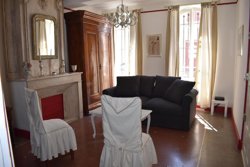 a living room with a black couch and two white chairs at Maison ARUM - Arles, centre historique in Arles