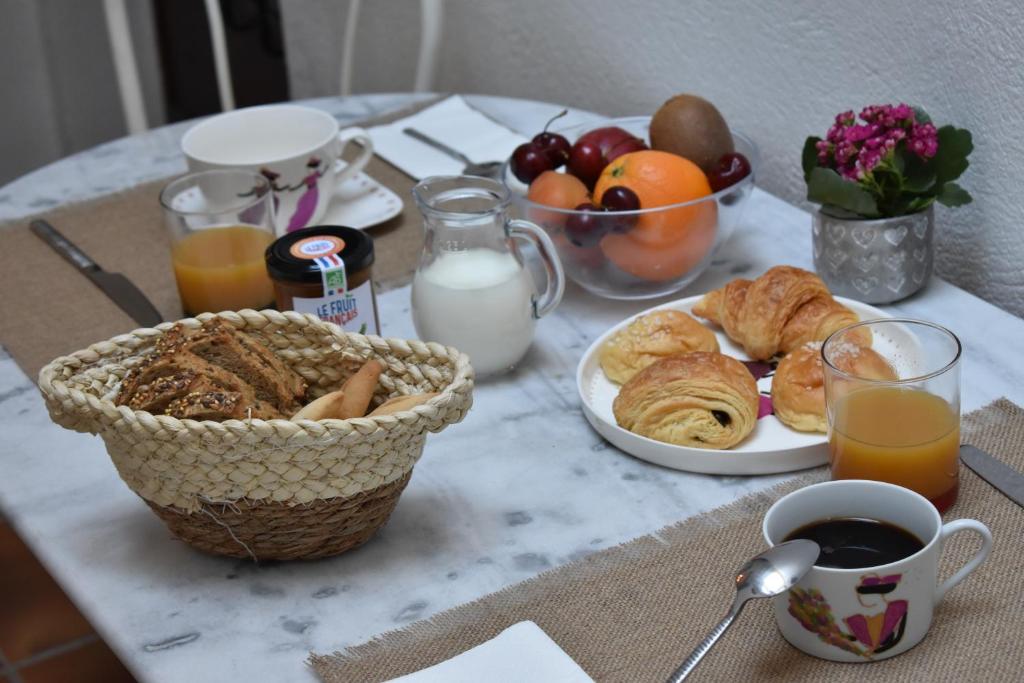 a table with a breakfast of pastries and orange juice at Maison ARUM - Arles, centre historique in Arles