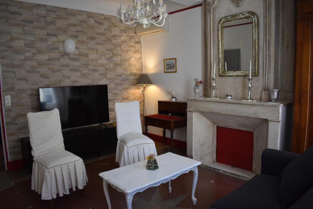 a living room with two white chairs and a fireplace at Maison ARUM - Arles, centre historique in Arles