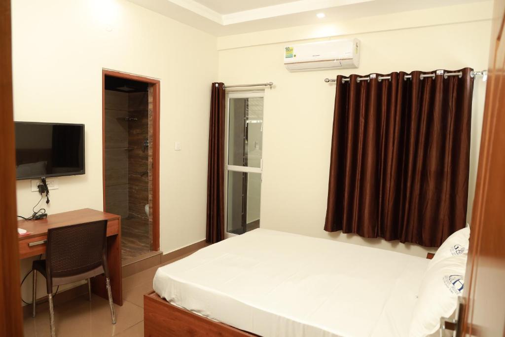 a bedroom with a bed and a desk and a television at Grace Apart Hotel @Kochi in Cochin
