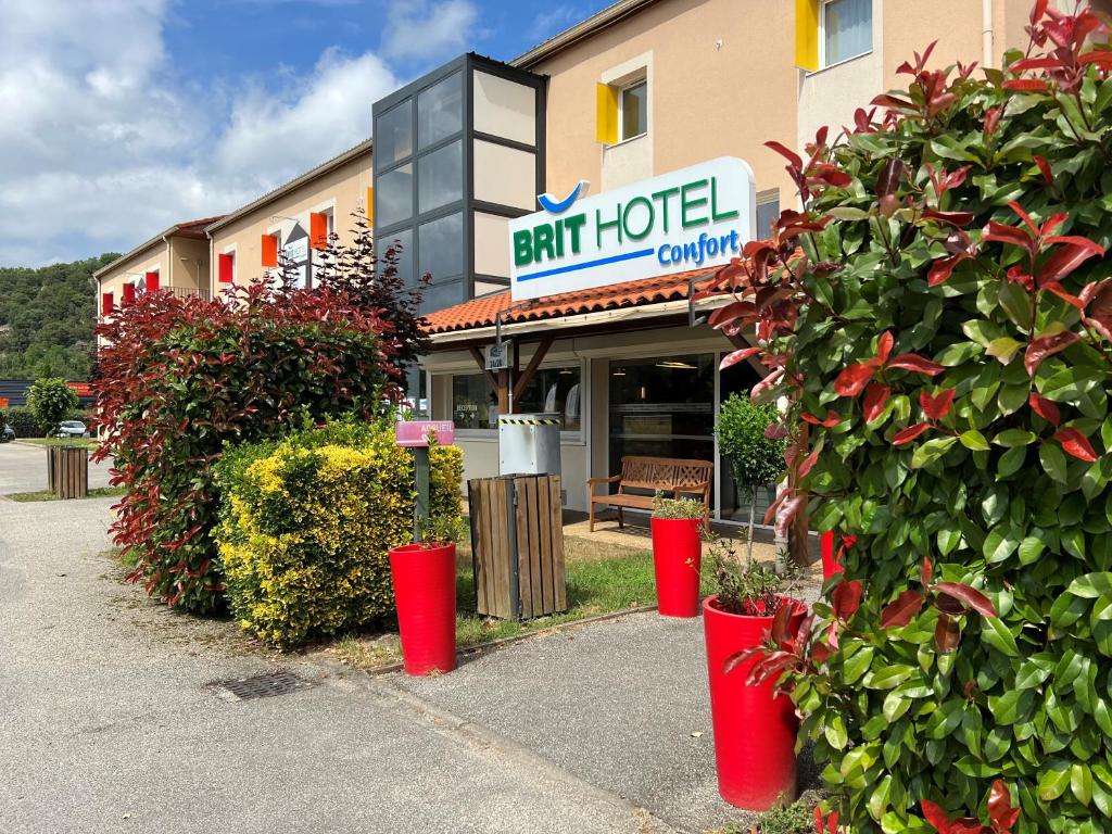 um restaurante com baldes vermelhos em frente a um edifício em Brit Hotel Confort Foix em Foix