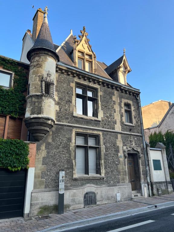 un vieux bâtiment en briques avec une tourelle dans une rue dans l'établissement Tournelles VUE CATHEDRALE- Maison Climatisée du XVIe siècle classée, à Reims